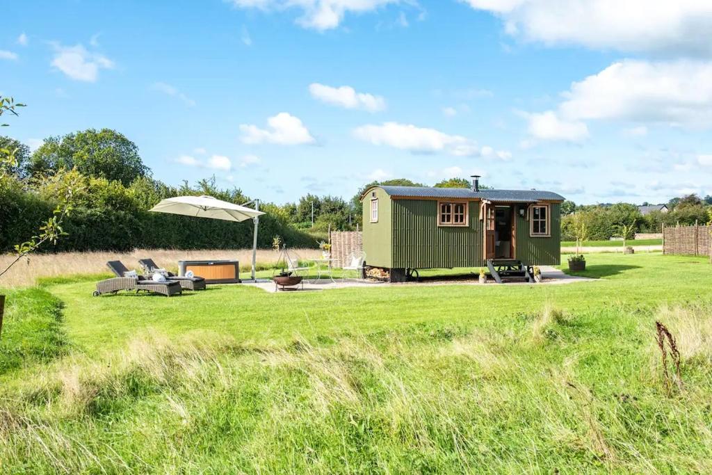 a green tiny house in the middle of a field at Black Mountain bespoke breaks in Brecon