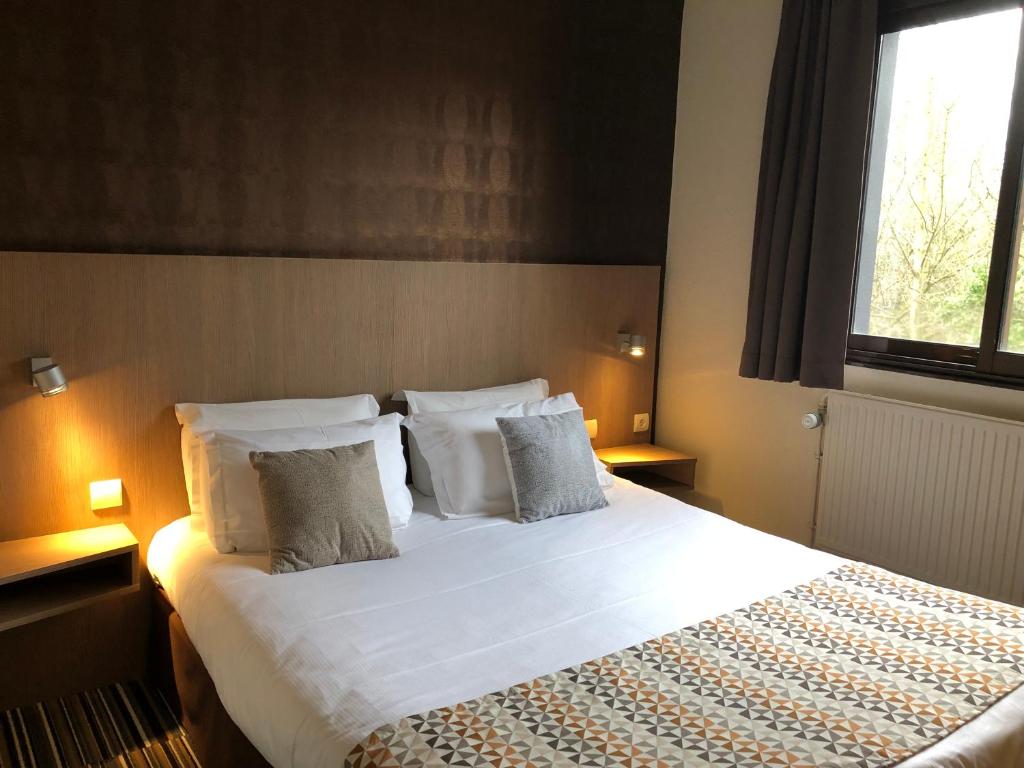 ein Schlafzimmer mit einem großen Bett mit weißer Bettwäsche und Kissen in der Unterkunft Hotel Bollaert in Lens