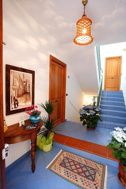 ein Zimmer mit Treppe, einem Tisch und Blumen in der Unterkunft La Chiusa Case Vacanze in Castellammare del Golfo