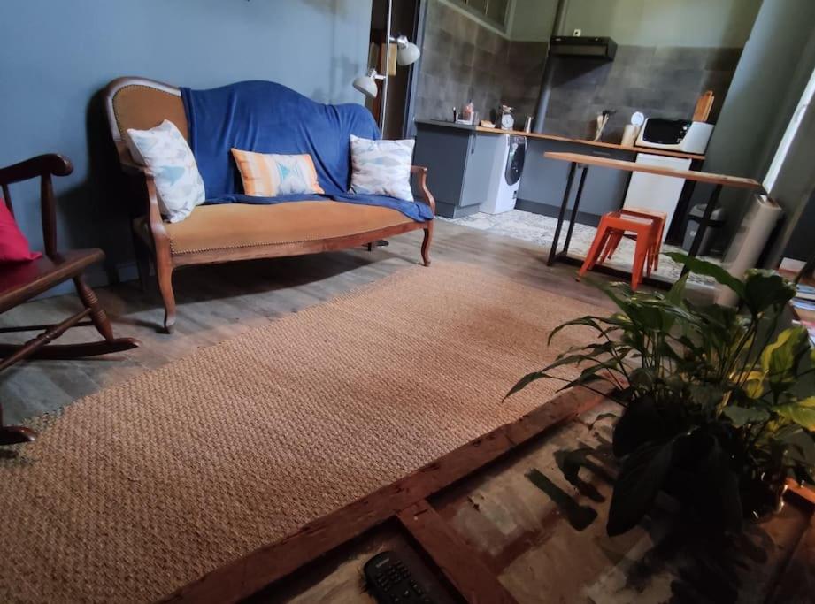 uma sala de estar com um sofá azul e uma mesa em Numéro 12, appartement douillet em Montauban