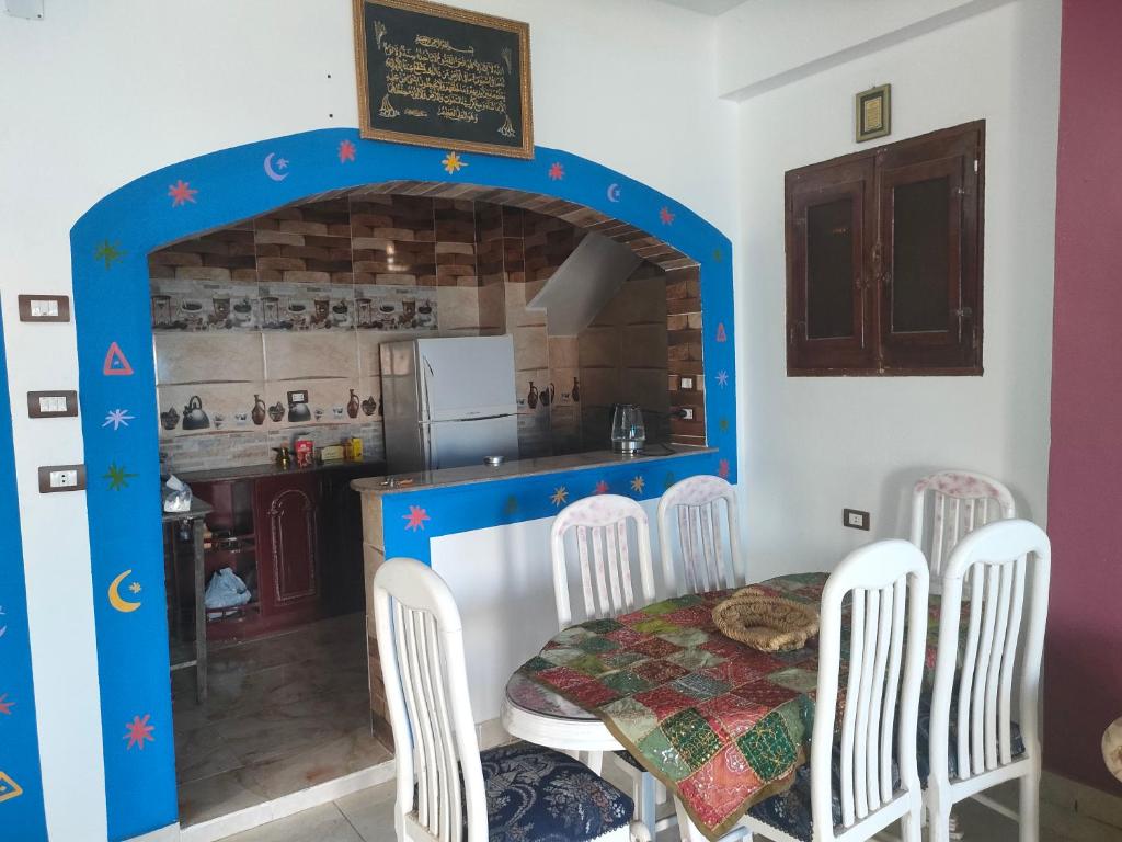 een eetkamer met een tafel en stoelen en een keuken bij Nukud guest house in Aswan