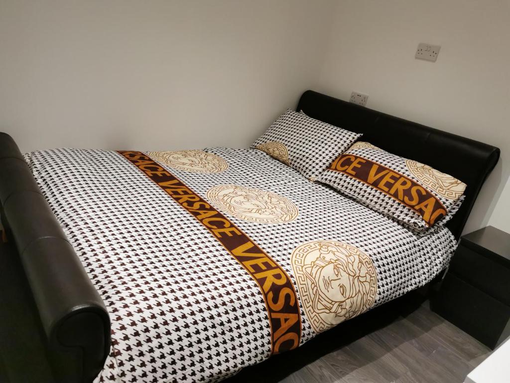 a bed with a black and white comforter and pillows at Studio self contained double bedroom in London