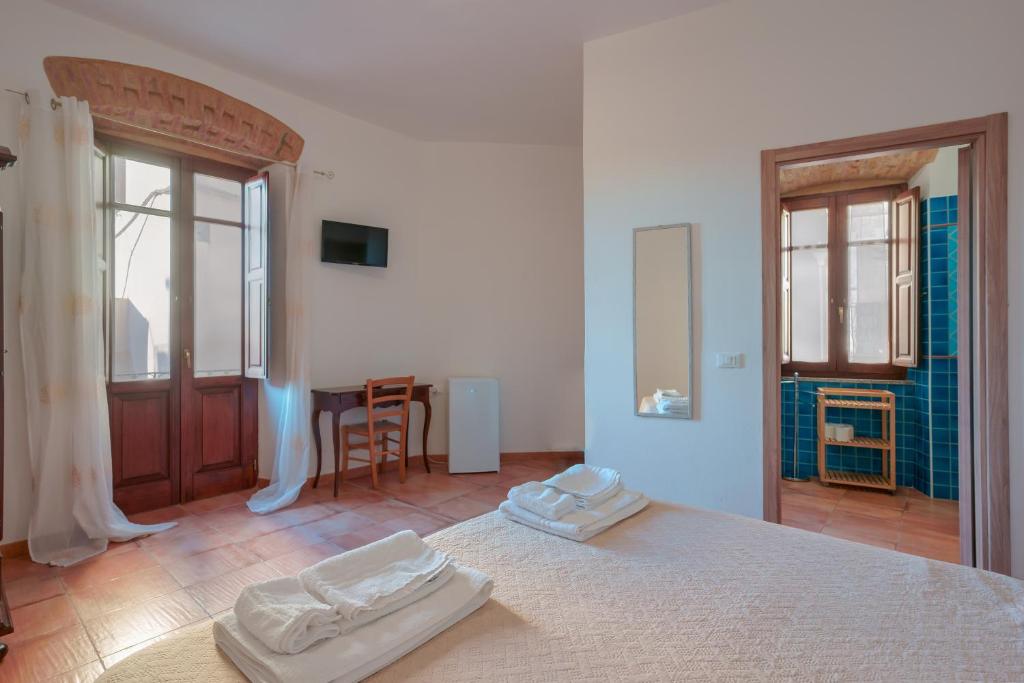 a white bedroom with two white towels on a bed at La Scala del Sale in Iglesias