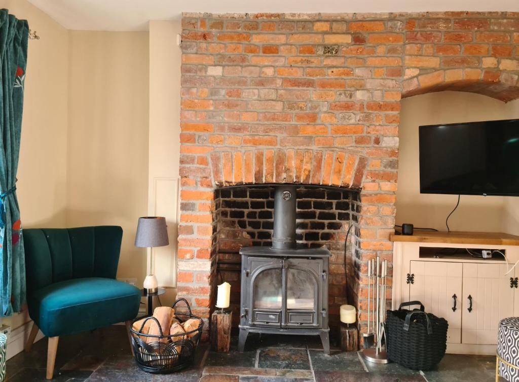 a living room with a brick fireplace and a tv at Gorgeous 2 bedroom Kintbury cottage in Kintbury