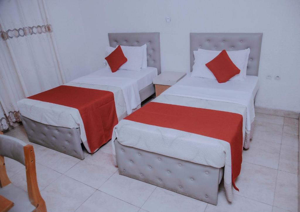 Habitación con 2 camas y almohadas rojas y blancas. en Room in BB - Martin Aviator Hotel, en Kigali