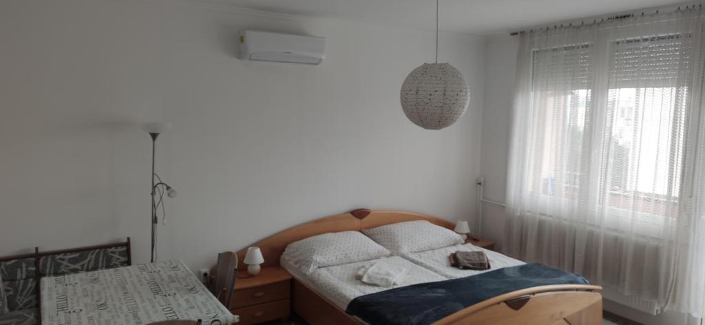 a white bedroom with a bed and a window at Csiga Apartment in Sárvár