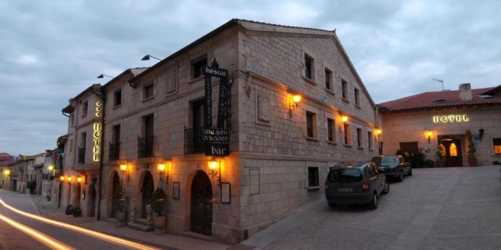 Un edificio en una calle con coches aparcados delante. en Hostal Santo Domingo de Silos, en Santo Domingo de Silos