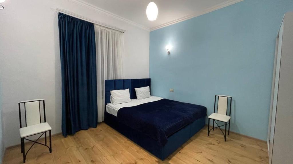 - une chambre avec un lit bleu et deux chaises dans l'établissement Ashtarak Garden GuestHouse, à Ashtarak