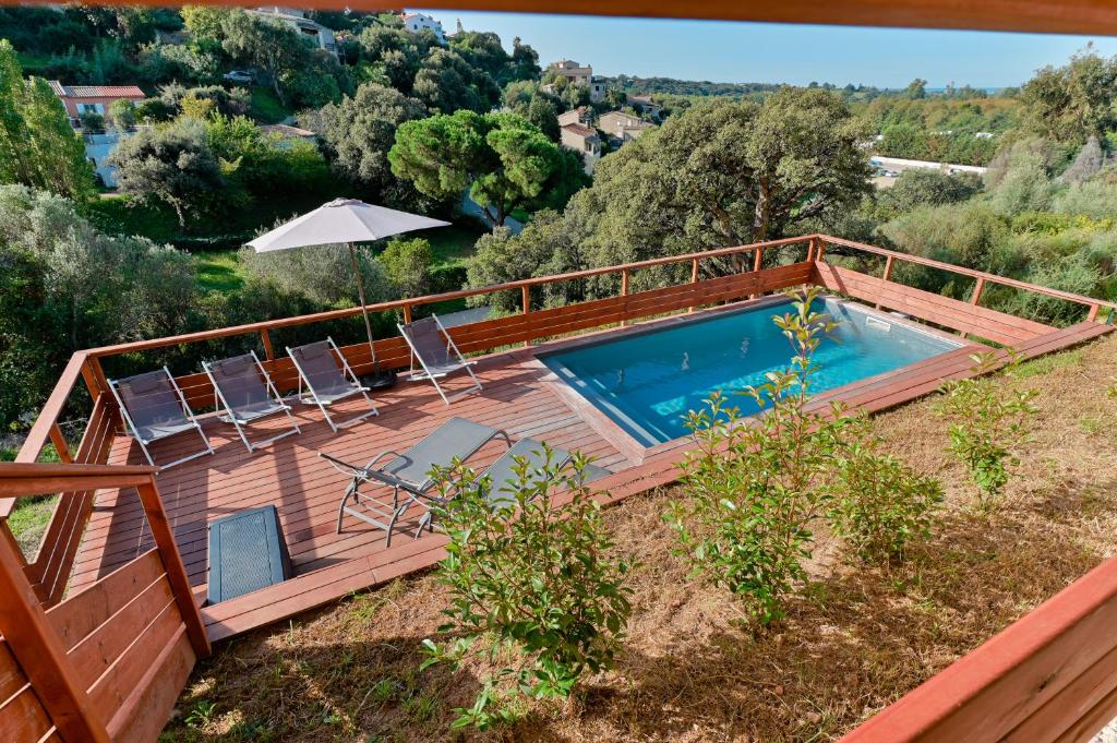 een terras met een zwembad en stoelen en een parasol bij Villa Terrasse et Piscine à l'entrée de Porticcio in Cauro