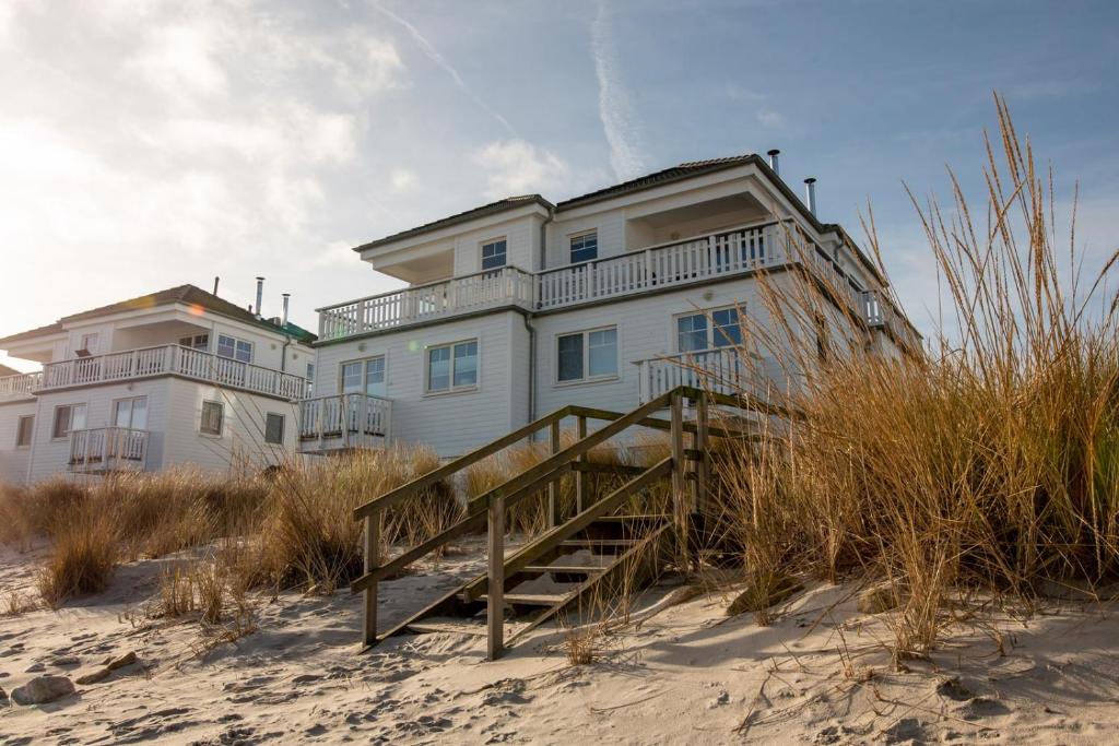 a large building on the beach with a wooden staircase at The Beach House in Olpenitz