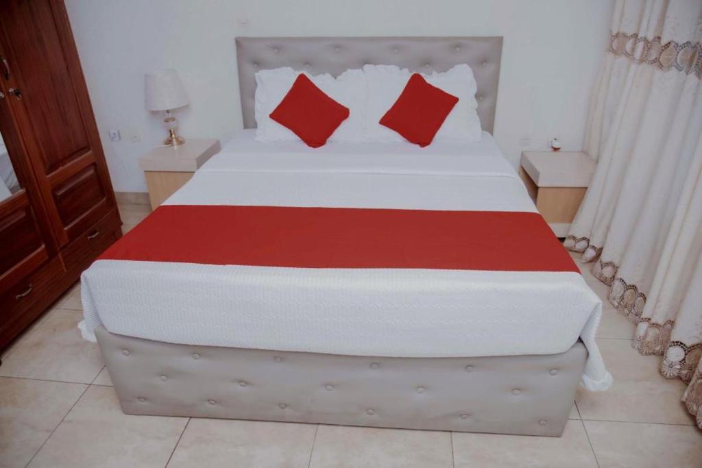 1 dormitorio con 1 cama grande con almohadas rojas en Room in BB - Martin Aviator Hotel en Kigali