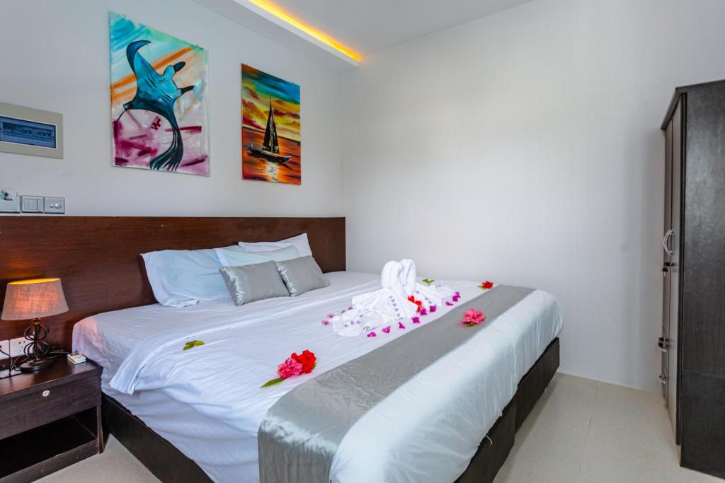 a bedroom with a large white bed with flowers on it at Violet Inn Hotel in Dharavandhoo