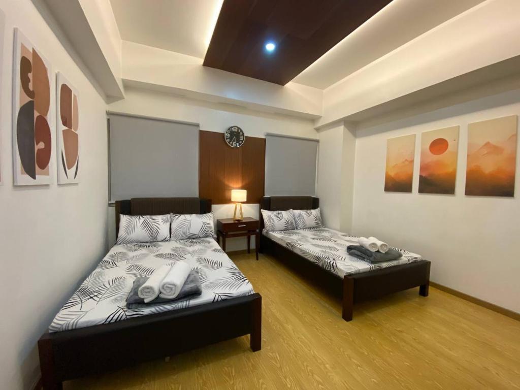 een kamer met 2 bedden en een tafel met een lamp bij CedarPeak213b in Baguio