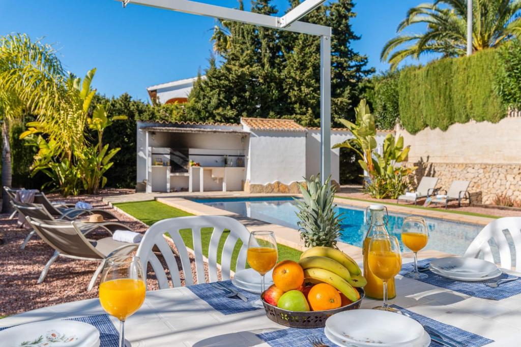 a table with a bowl of fruit next to a pool at Villa Padilla - PlusHolidays in Benissa