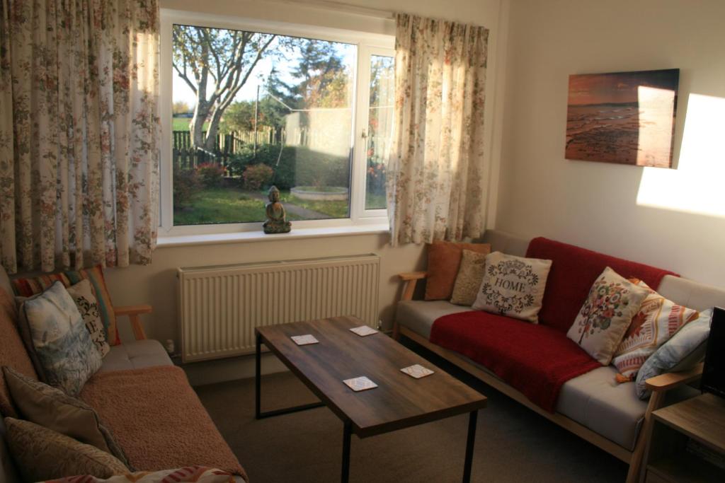 a living room with a couch and a table and a window at Simla Bungalow, Tetney in Tetney