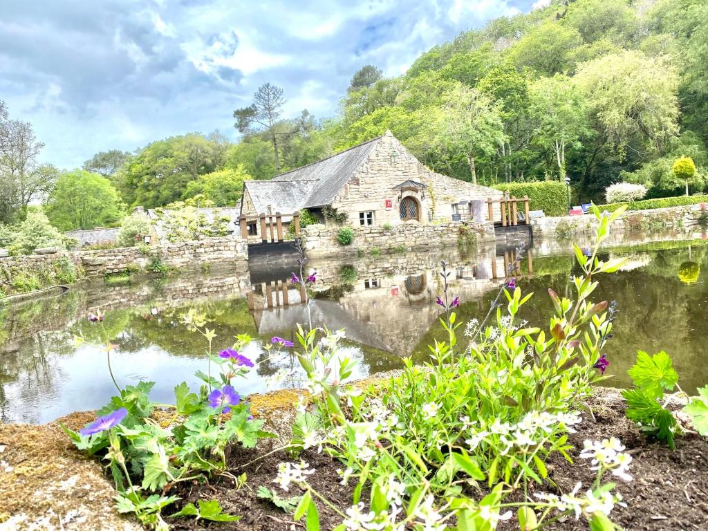 an old house in the middle of a pond with flowers at Les Moulins Du Duc ÉCOLODGE in Moëlan-sur-Mer