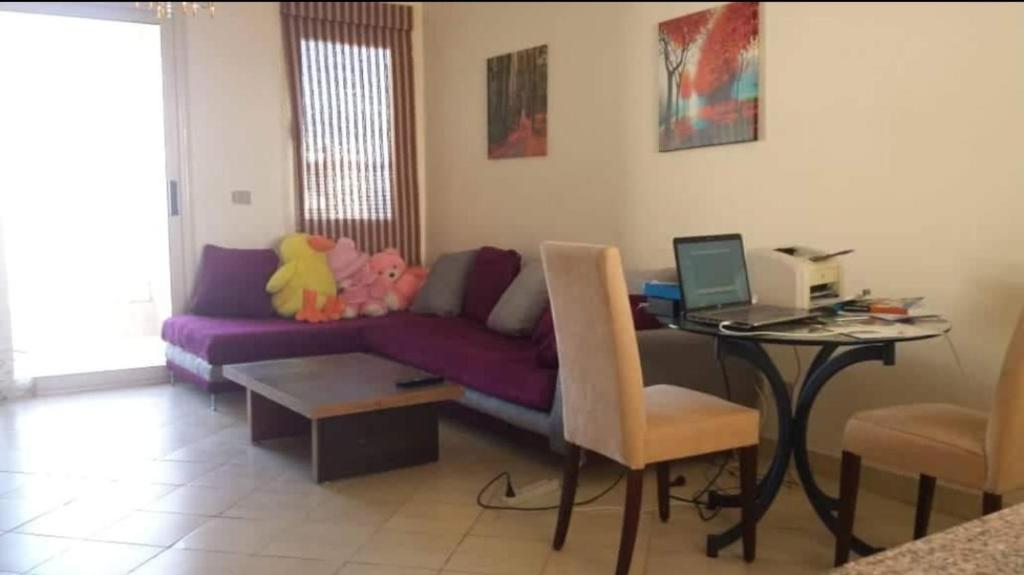 a living room with a purple couch and a table with a laptop at شرم الشيخ قرية الليمار in Ash Shaţţ