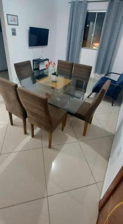 una sala da pranzo con tavolo, sedie e TV di Aconchego Familiar Veredas a Viçosa