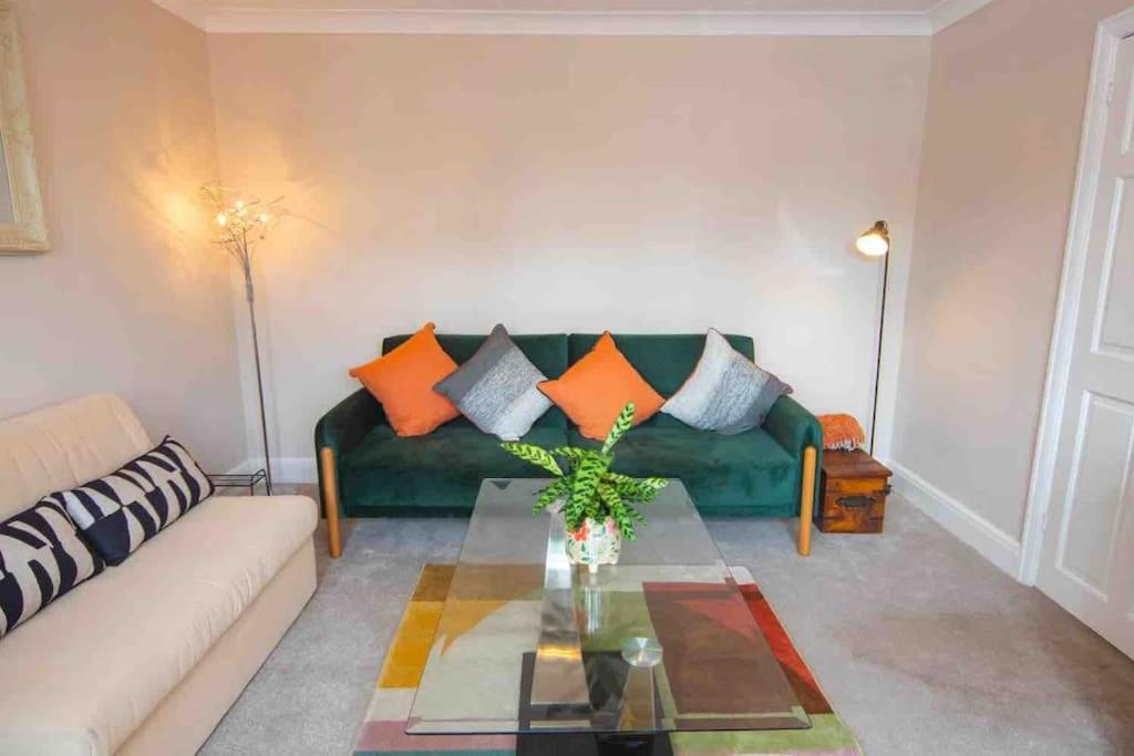 a living room with a green couch with orange pillows at 1 Bedroom self contained apartment in Christchurch in Winkton