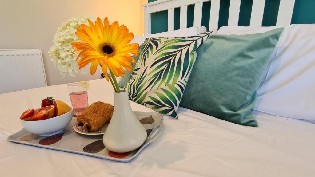 a vase with a flower and a plate of food on a bed at Worthingtons by Spires Accommodation A cosy and comfortable home from home place to stay in Burton-upon-Trent in Burton upon Trent
