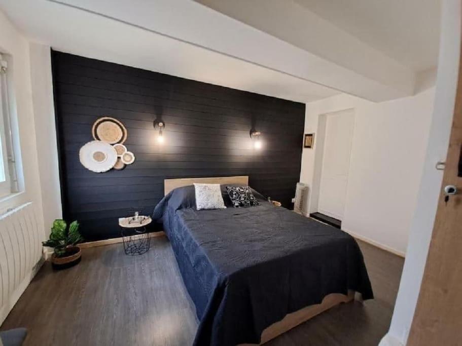 - une chambre avec un lit et un mur noir dans l'établissement la Lillebonnaise meublé au cœur de Lillebonne, à Lillebonne