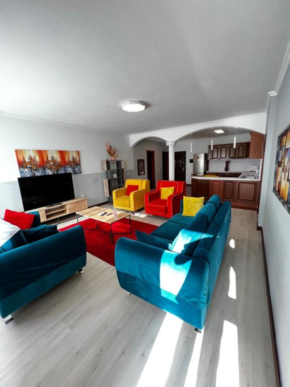 a living room with a blue couch and colorful chairs at SunShine APARTMENT in Tirana