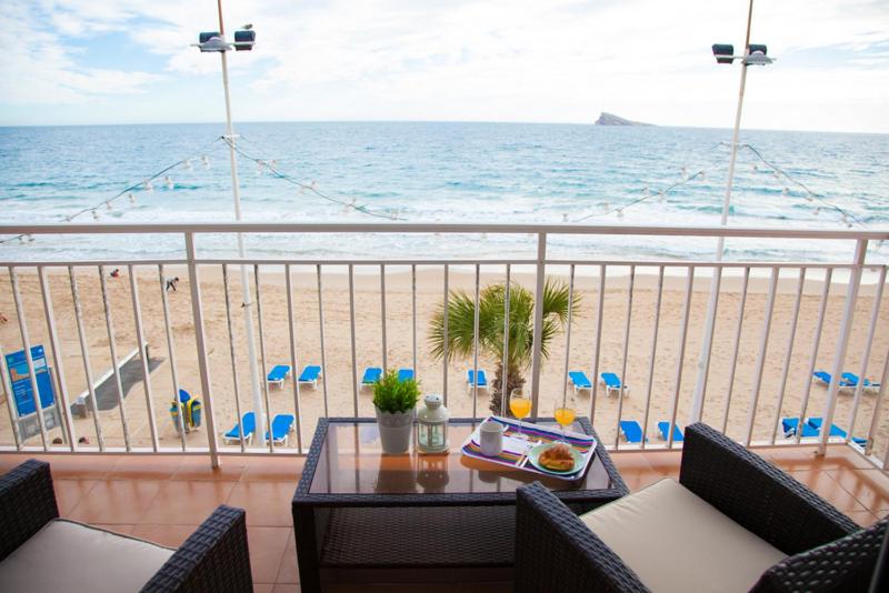a balcony with a table and chairs and the beach at SEAFRONT UNBEATABLE LOCATION a in Benidorm