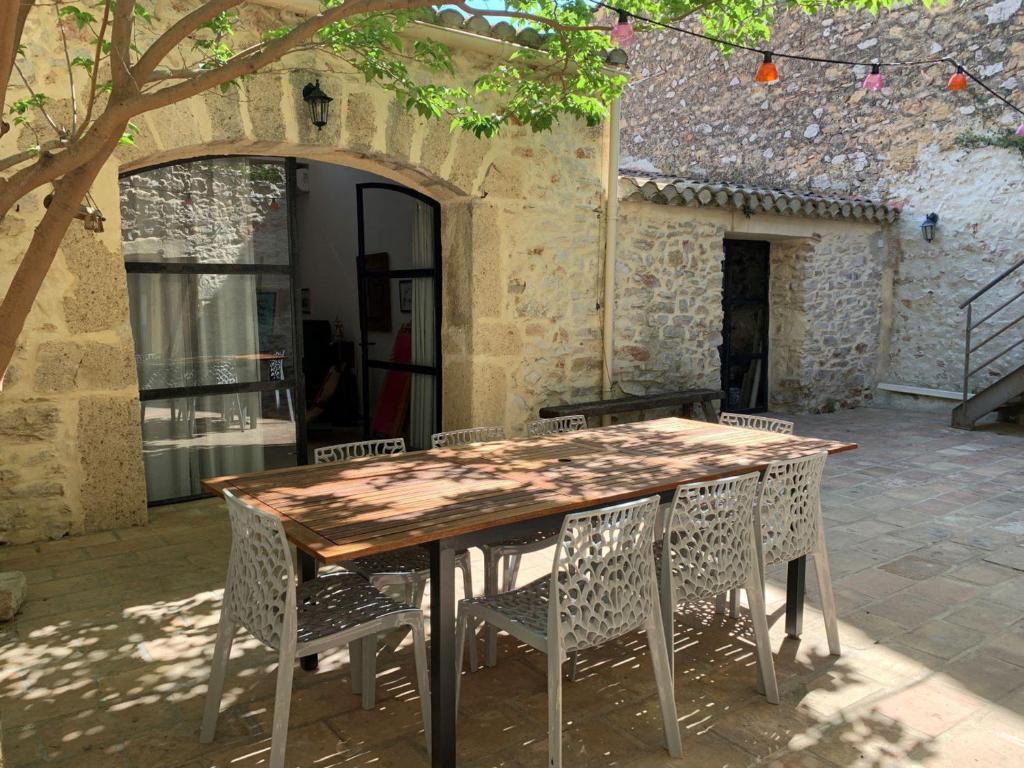 une table et des chaises en bois devant un bâtiment dans l'établissement Charmante maison climatisée avec cour privée à Bouzigues, idéal pour vacances en famille ou entre amis - FR-1-604-16, à Bouzigues