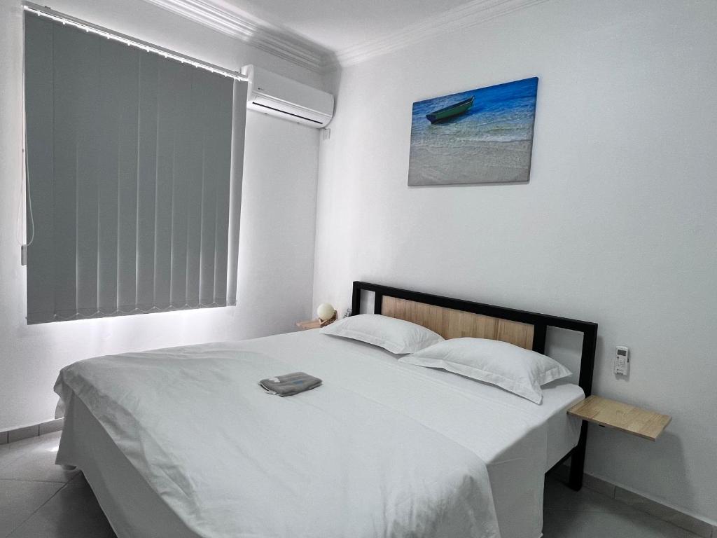 a white bedroom with a large bed and a window at Sunshine Residence in Poste Lafayette