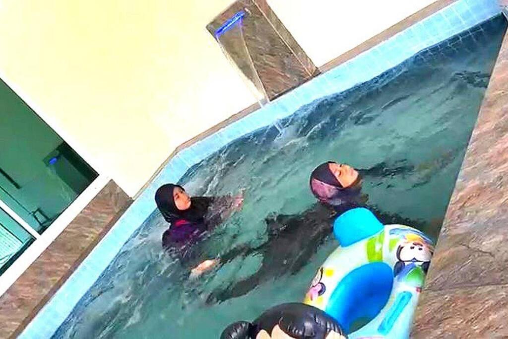 eine Gruppe von Personen, die in einem Schwimmbad schwimmen in der Unterkunft Desaru 16Pax Family with Private Mini Pool & Jacuzzi in Kota Tinggi
