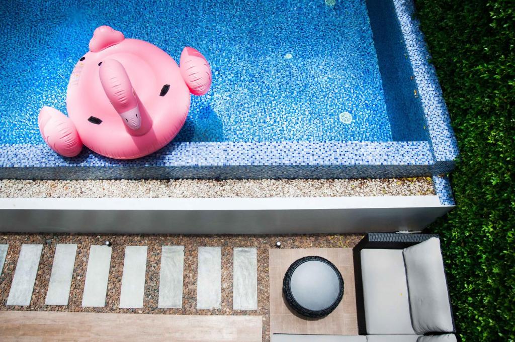 um porco rosa de brinquedo sentado numa piscina em Movenpick Pool villa by Angkana em Na Jomtien