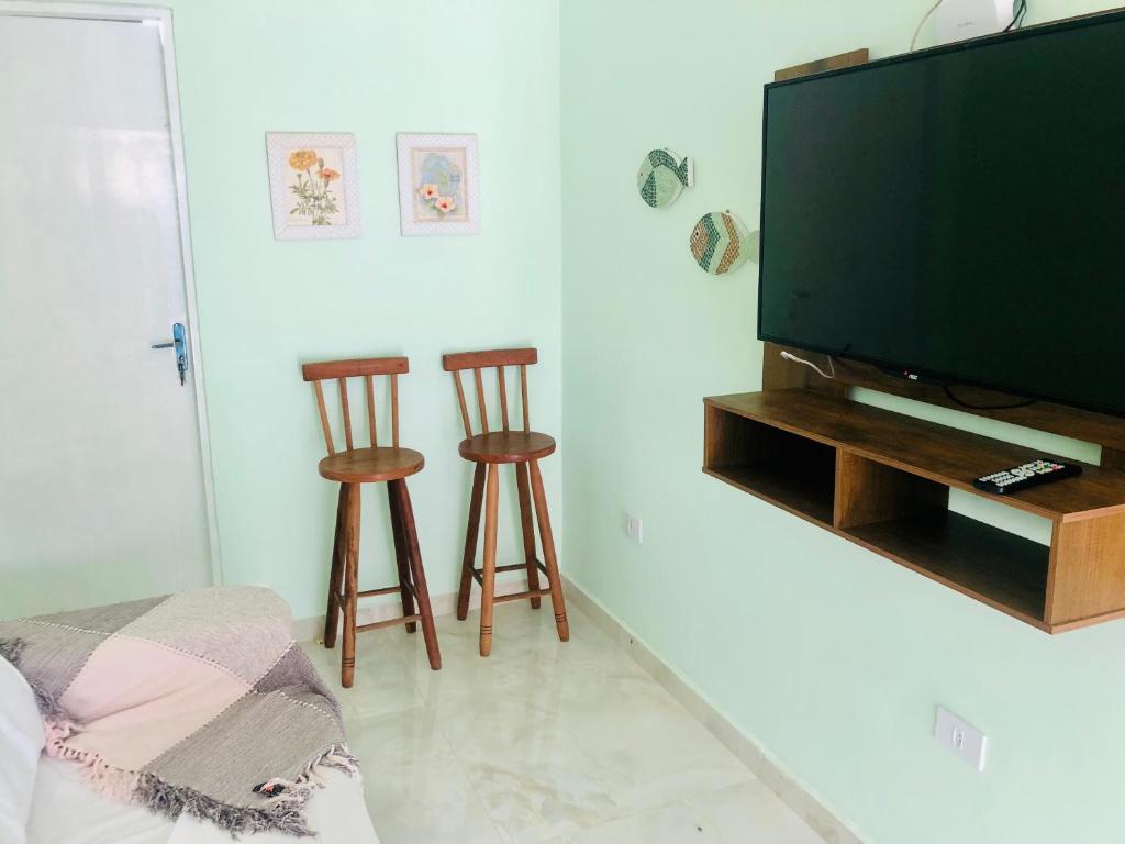 a living room with a flat screen tv and two stools at Casa Gris in Praia Grande