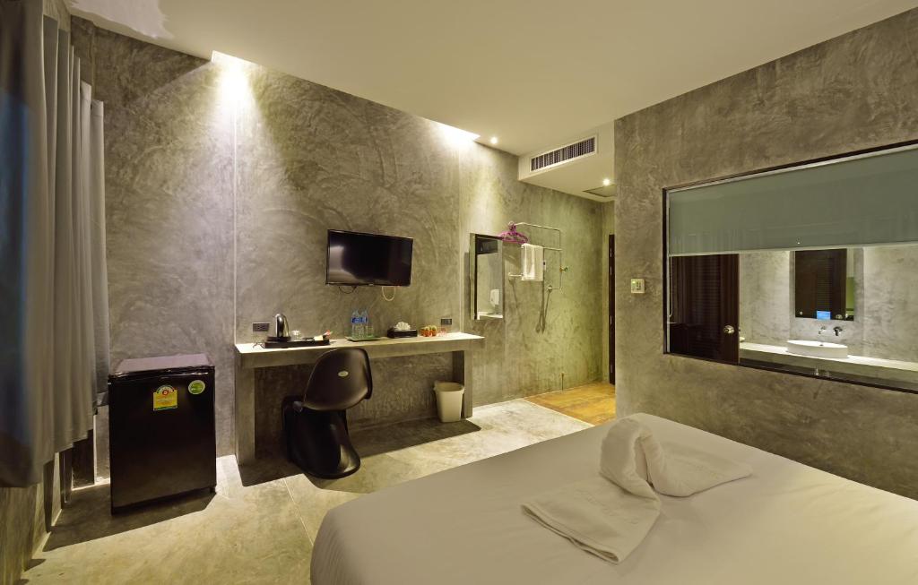 um quarto de hotel com uma cama, uma secretária e uma televisão em The Oasis Resort em Krabi
