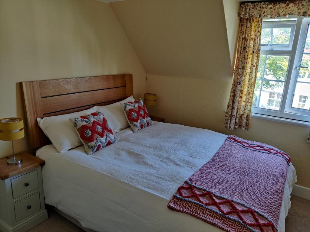 a bedroom with a bed with pillows and a window at April cottage in Winchelsea