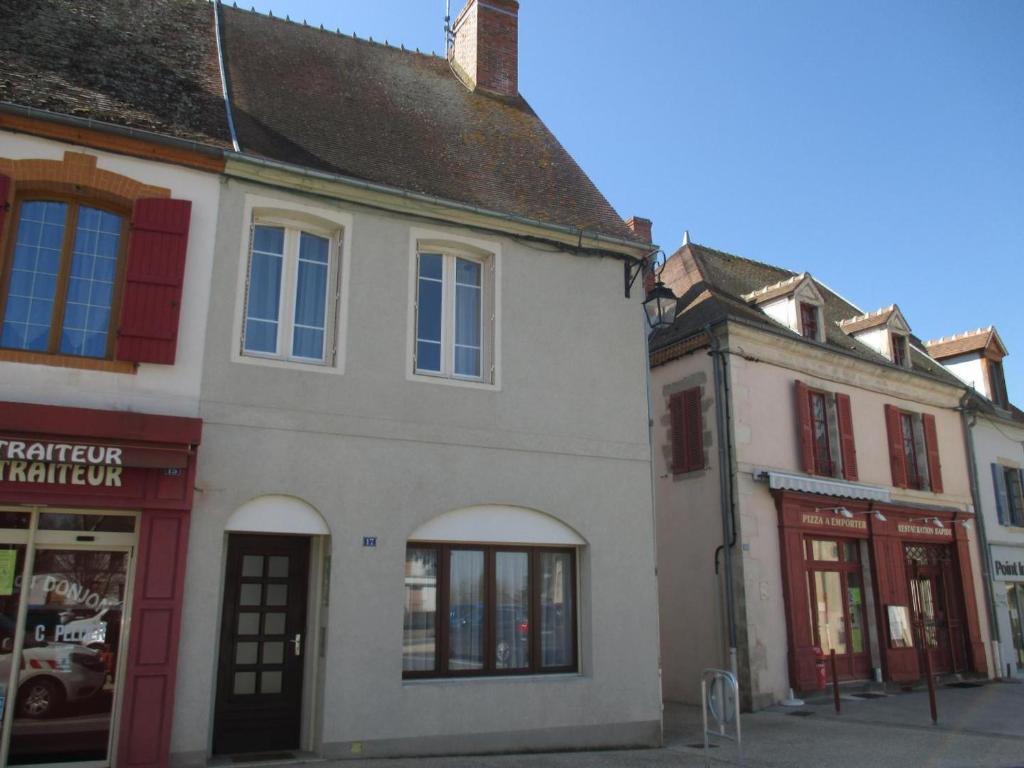 een oud wit gebouw met rode deuren en ramen bij Gîte Huriel, 4 pièces, 5 personnes - FR-1-489-27 in Huriel