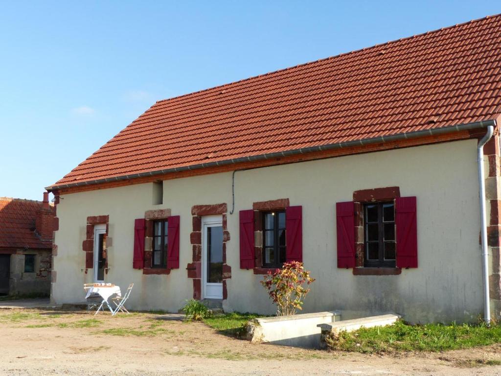 ein weißes Haus mit roten Fensterläden und einem Tisch in der Unterkunft Gîte Vaumas, 5 pièces, 8 personnes - FR-1-489-99 in Vaumas