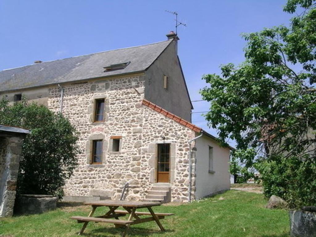 een stenen gebouw met een picknicktafel ervoor bij Gîte Nizerolles, 4 pièces, 8 personnes - FR-1-489-137 in Nizerolles