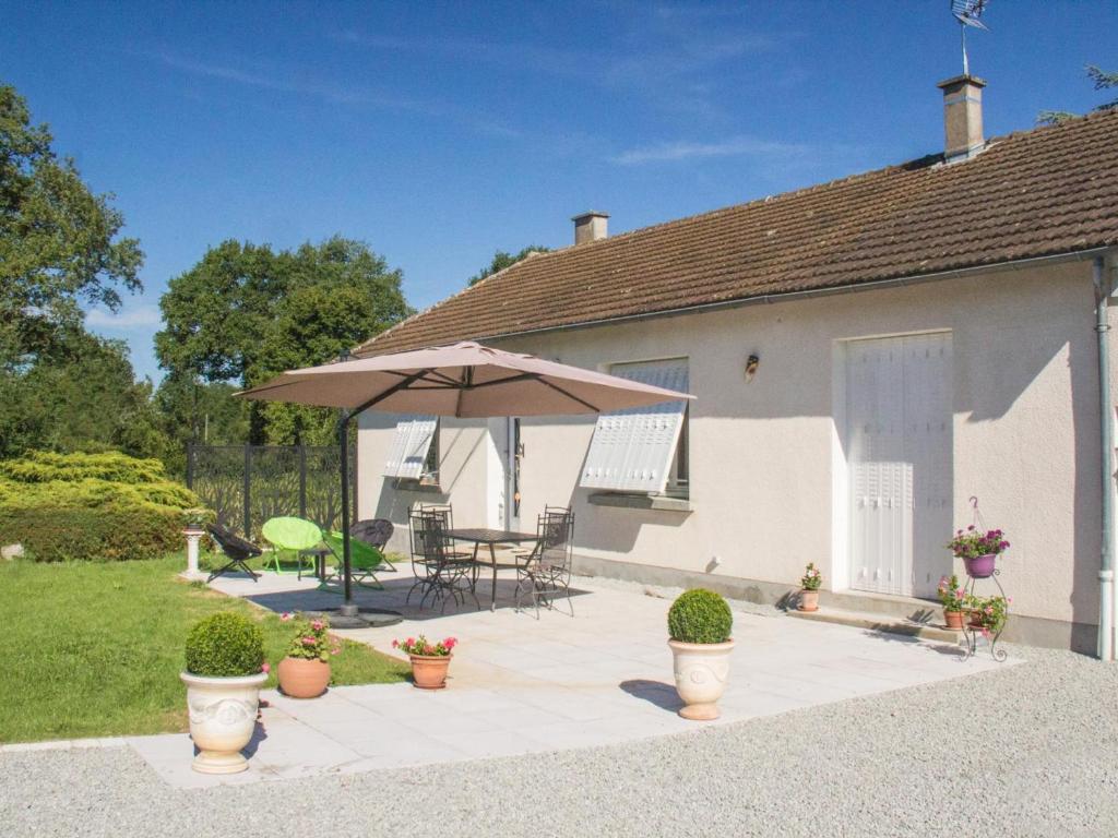 a patio with a table and an umbrella at Gîte familial en Auvergne avec jardin, ping-pong, proche stations thermales, animaux acceptés - FR-1-489-127 in Mazirat