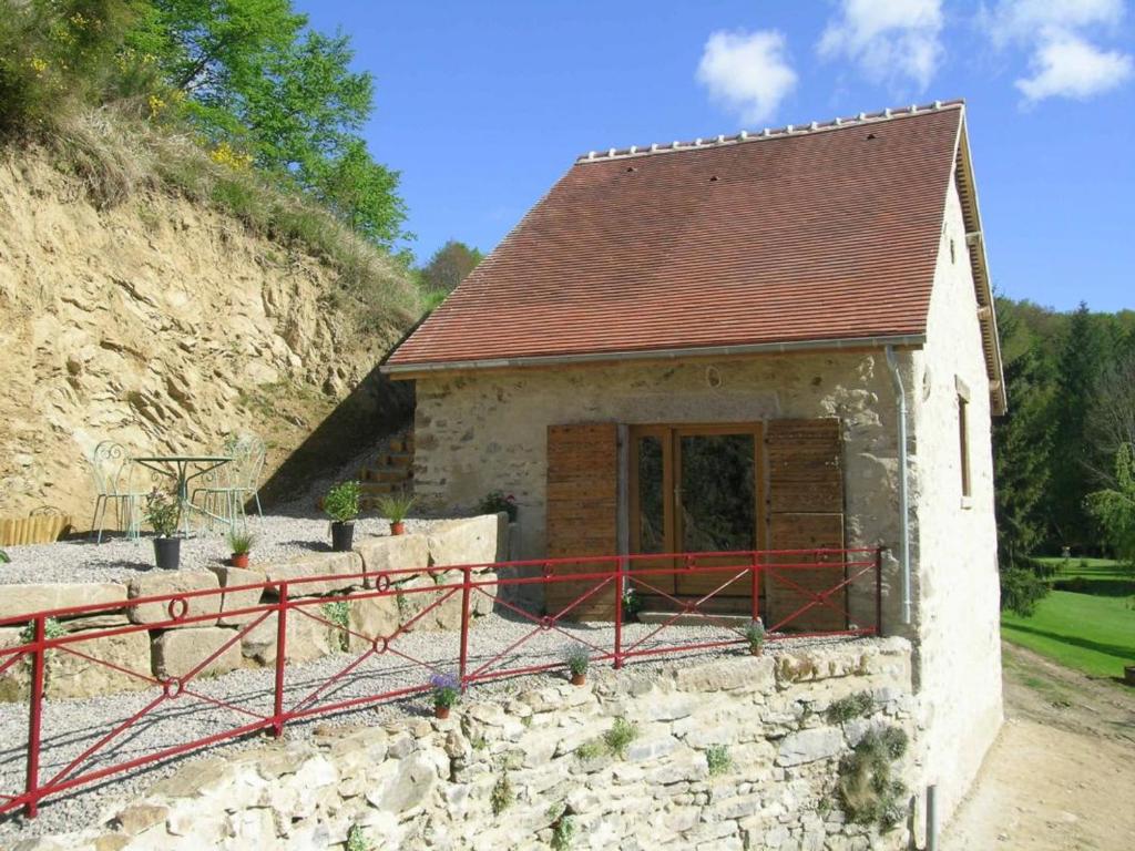 uma pequena casa de pedra com uma cerca vermelha à volta em Gîte Vernusse, 2 pièces, 2 personnes - FR-1-489-208 em Vernusse