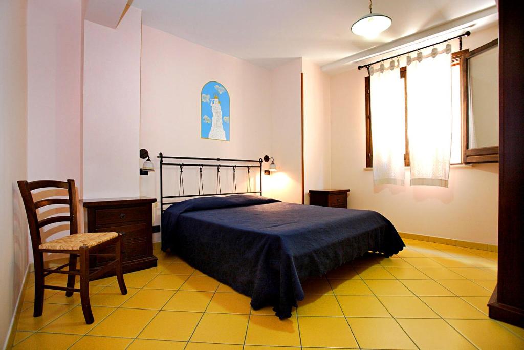 1 dormitorio con cama, silla y ventana en La Chiusa Case Vacanze, en Castellammare del Golfo