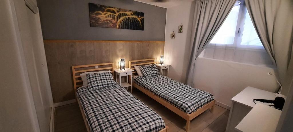 two beds in a small room with a window at Lanzarote-Beach-Apartment, Las Cucharas Beach, Costa Teguise -- 1 MINUTE WALK FROM MAIN SQUARE, 35 METERS FROM BEACH in Costa Teguise