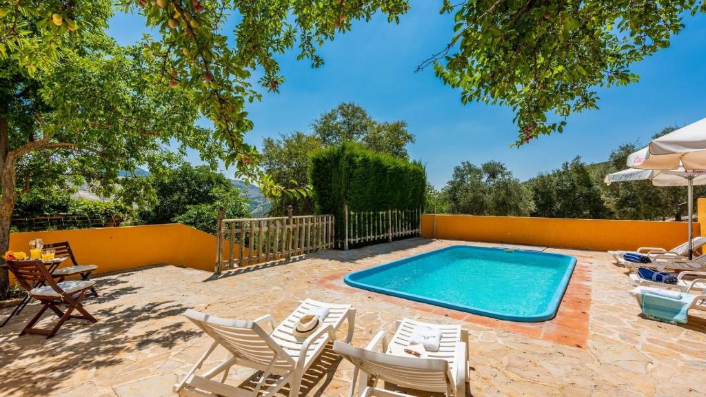 een zwembad met stoelen, een tafel en een parasol bij Cortijo Coracho Osuna by Ruralidays in Saucejo