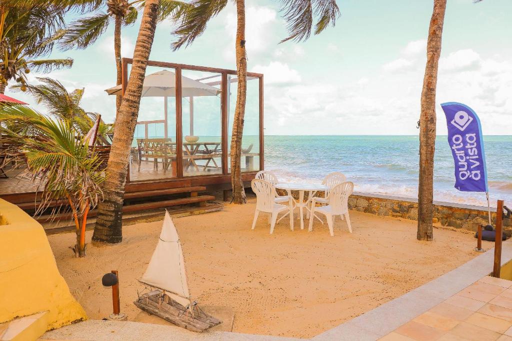 einen Tisch und Stühle am Strand mit Meerblick in der Unterkunft Qavi - Villa Jacumã #Luxo in Jacumã