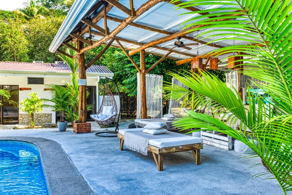 a patio with a pool and a wooden pergola at Tribe Boutique Hotel - Adults Only in Dominical