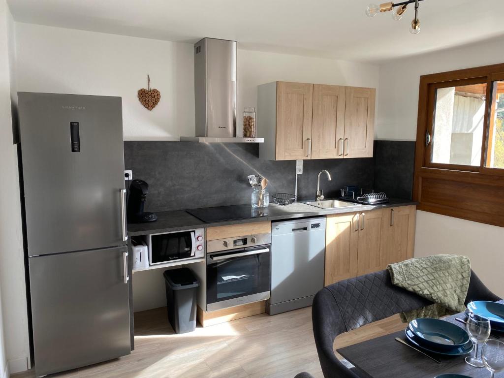 eine Küche mit einem Kühlschrank aus Edelstahl und einem Tisch in der Unterkunft Appartement Le Lauzet in La Roche-de-Rame