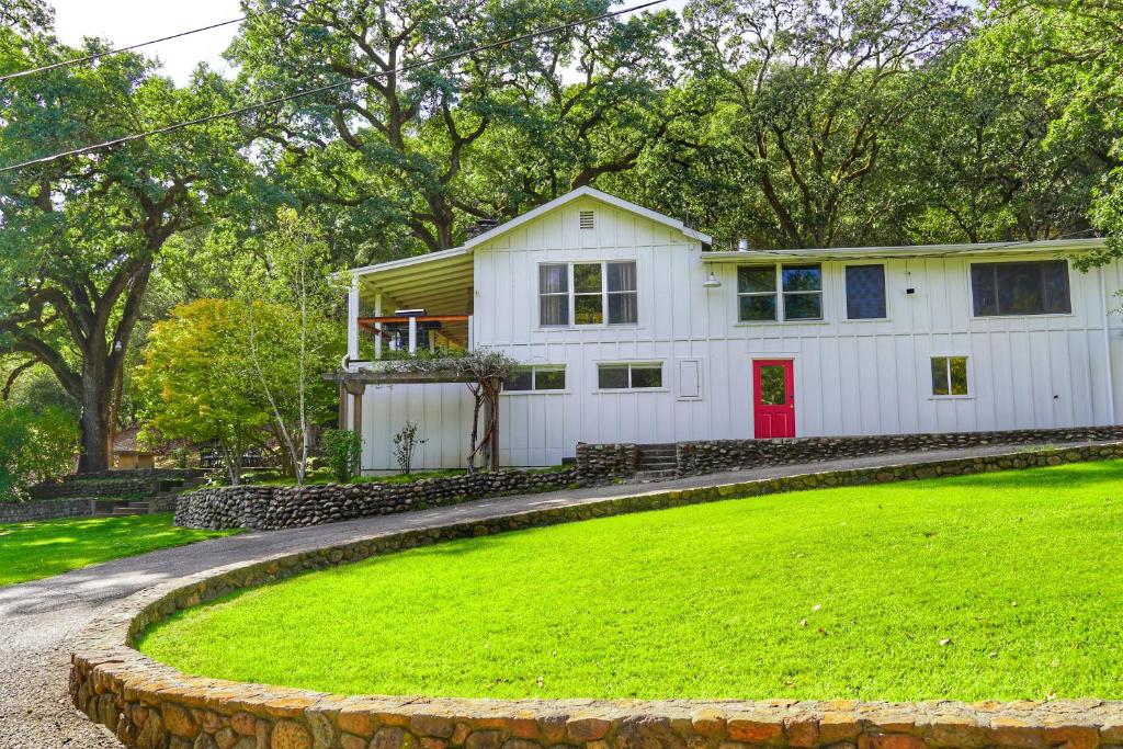 una casa blanca con una puerta roja en un patio verde en Mayacamas Retreat, en Santa Rosa