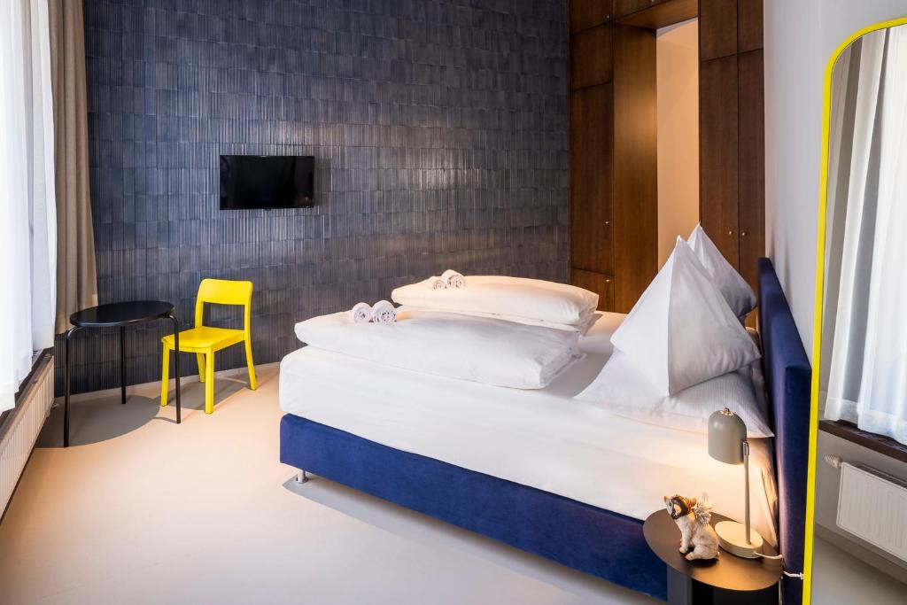 a bedroom with a bed and a yellow chair at grätzlhotel Serviten in Vienna