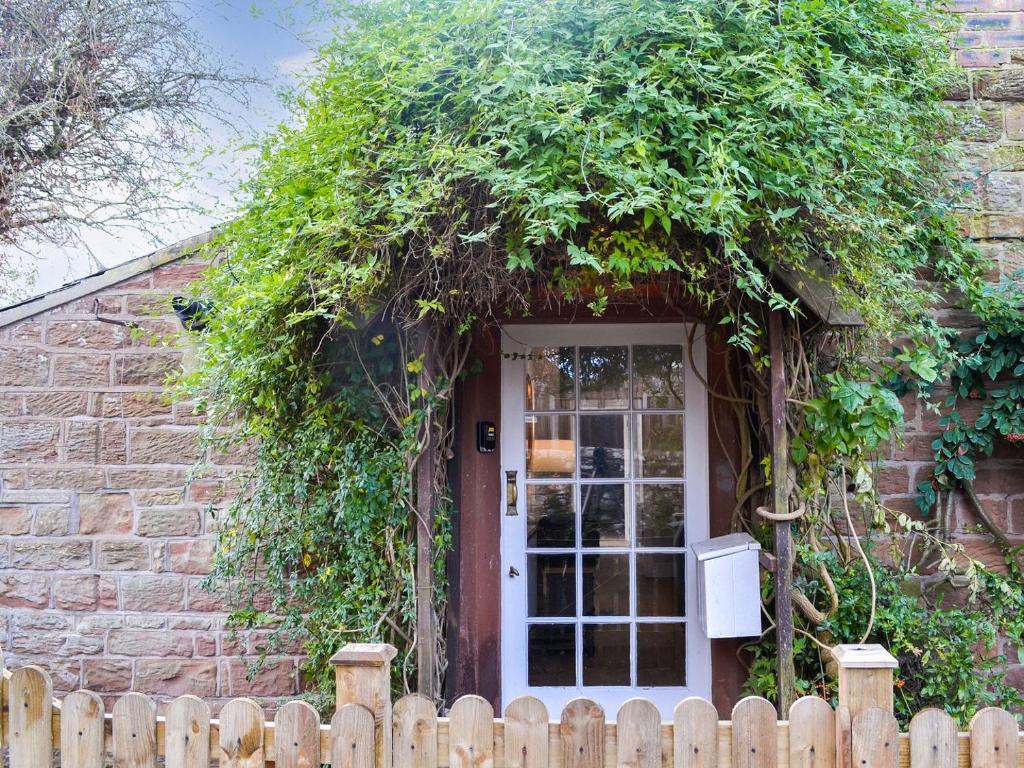 una casa de ladrillo con una puerta blanca con hiedra en Biskey Howe, en Newby