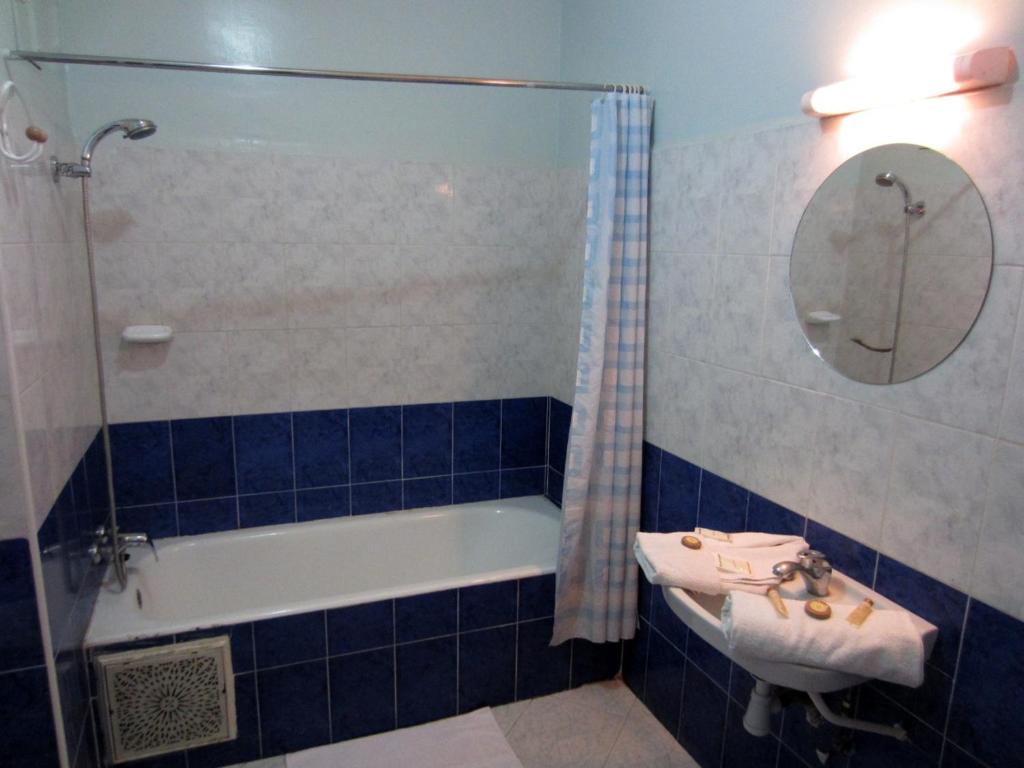 W wyłożonej niebieskimi kafelkami łazience znajduje się umywalka i wanna. w obiekcie Marrakech Hôtel Résidence w Marakeszu