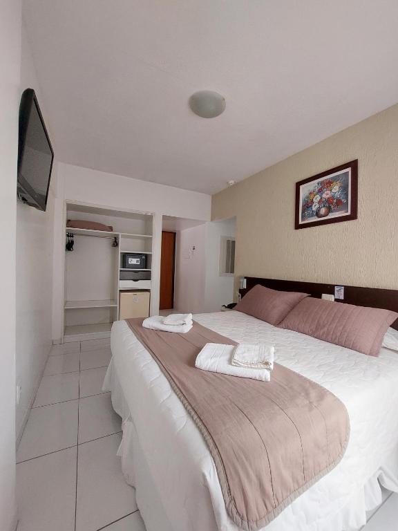 a bedroom with a large bed with a tv on the wall at Hotel Vela Azul in Balneário Camboriú